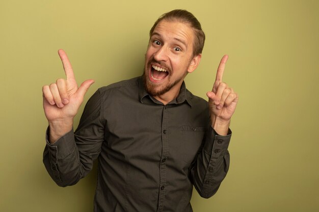 Hombre guapo joven en camisa gris feliz y sorprendido mostrando los dedos índices