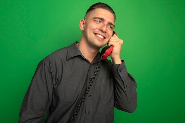 Foto gratuita hombre guapo joven en camisa gris hablando por teléfono vintage sonriendo alegremente