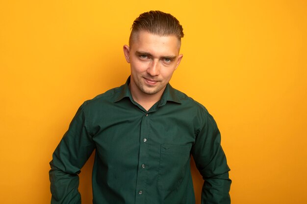 Hombre guapo joven en camisa verde sonriendo confiado