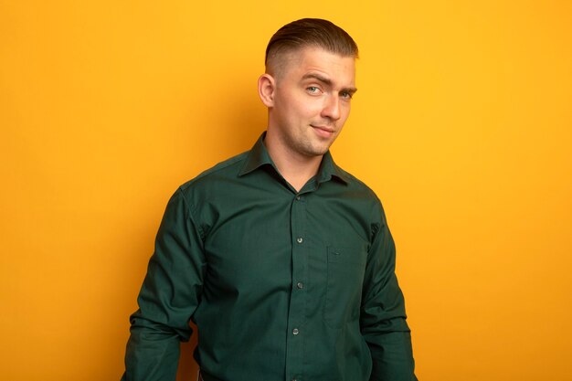 Hombre guapo joven en camisa verde con sonrisa escéptica