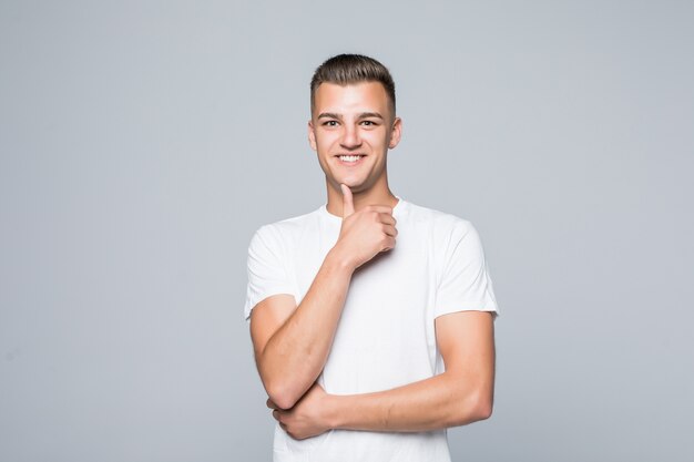 Hombre guapo joven en una camiseta blanca aislado en blanco mantenga el brazo debajo de la barbilla