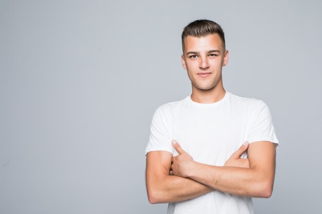 Hombre guapo joven en una camiseta blanca aislado en blanco mantenga los brazos cruzados