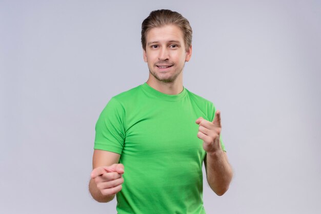 Hombre guapo joven con camiseta verde apuntando con los dedos