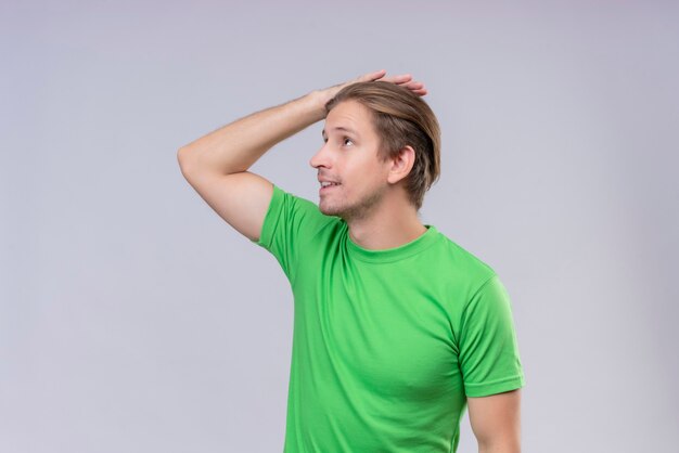 Hombre guapo joven con camiseta verde mirando a un lado