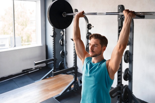 Hombre guapo joven entrenando en el gimnasio para culturismo