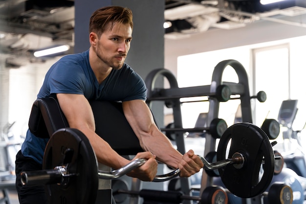 Foto gratuita hombre guapo joven entrenando en el gimnasio para culturismo