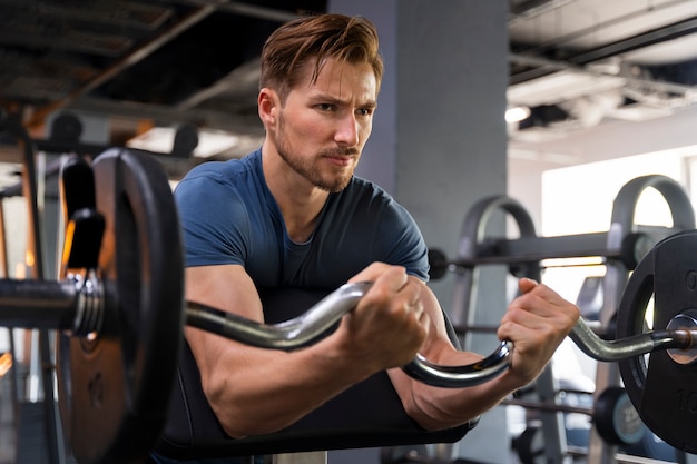 Foto gratuita hombre guapo joven entrenando en el gimnasio para culturismo