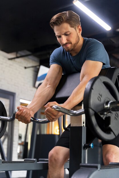 Hombre guapo joven entrenando en el gimnasio para culturismo