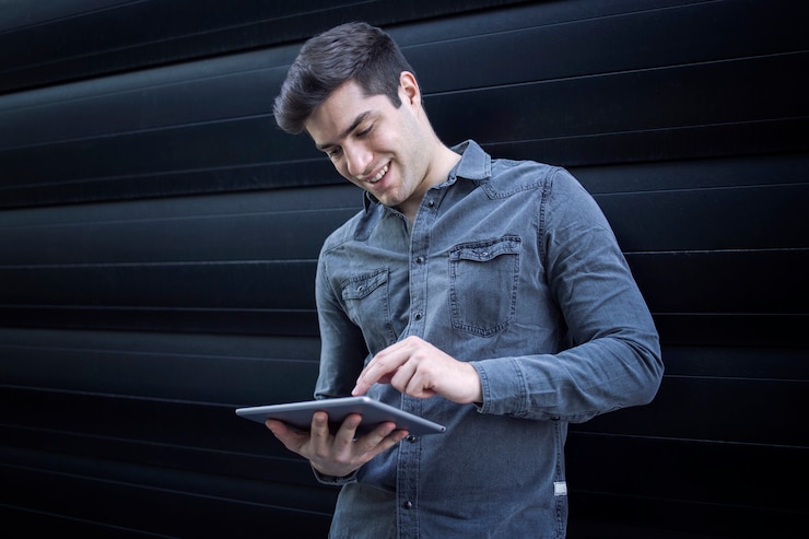 Foto gratuito hombre guapo joven escribiendo en su tableta