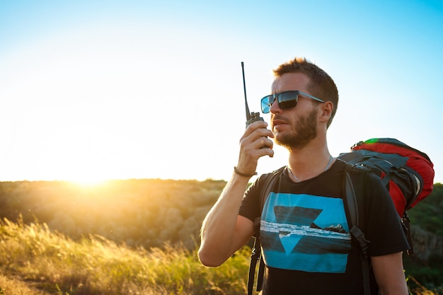 Hombre guapo joven hablando por radio walkie talkie, disfrutando de la vista del cañón