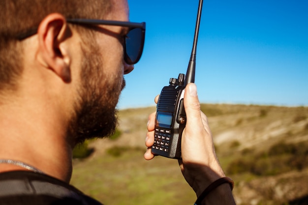 Hombre guapo joven hablando por radio walkie talkie, disfrutando de la vista del cañón