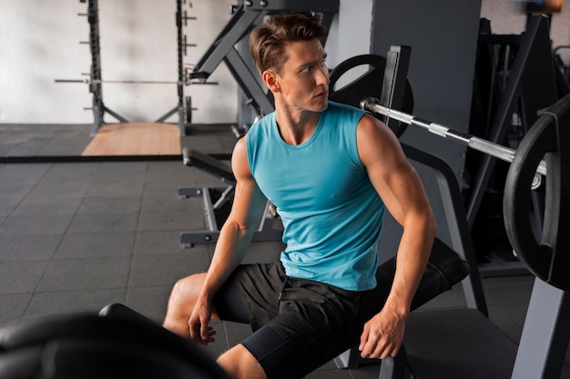 Hombre guapo joven haciendo ejercicio en el gimnasio para culturismo