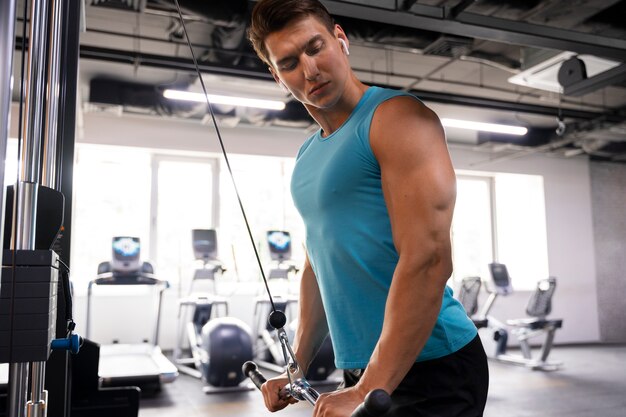 Hombre guapo joven haciendo ejercicio en el gimnasio para culturismo