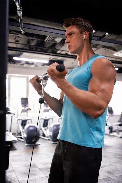 Hombre guapo joven haciendo ejercicio en el gimnasio para culturismo