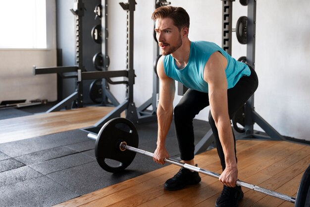 Hombre guapo joven haciendo ejercicio en el gimnasio para culturismo