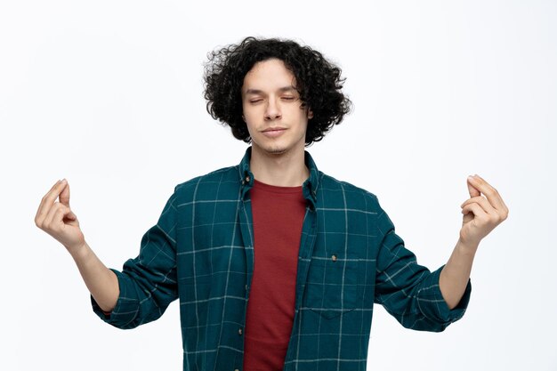 Hombre guapo joven pacífico meditando con los ojos cerrados aislado sobre fondo blanco.