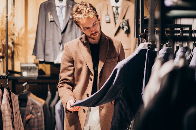 Hombre guapo joven que elige la ropa en la tienda