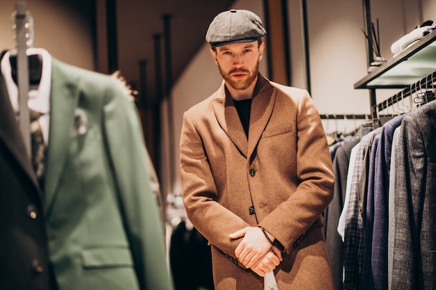 Hombre guapo joven que elige el sombrero en la tienda