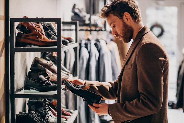 Hombre guapo joven que elige los zapatos en una tienda