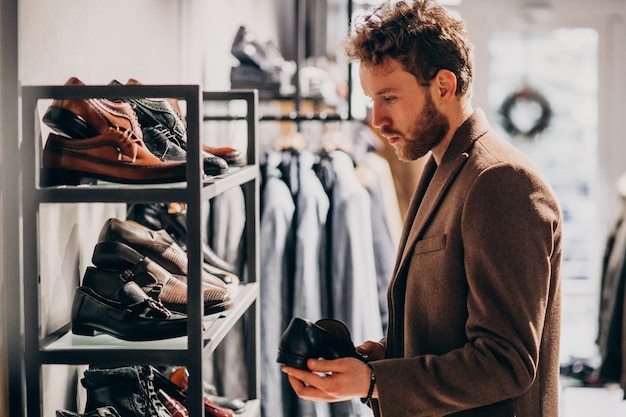 Hombre guapo joven que elige los zapatos en una tienda