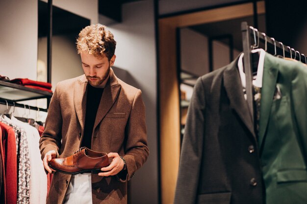 Hombre guapo joven que elige los zapatos en una tienda