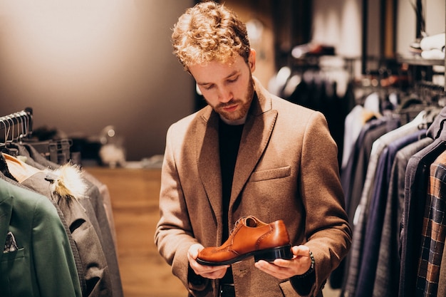 Hombre guapo joven que elige los zapatos en una tienda