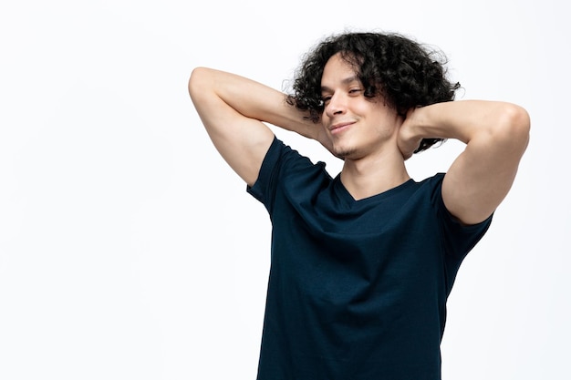 Foto gratuita hombre guapo joven relajado manteniendo las manos detrás del cuello mirando al lado aislado sobre fondo blanco.