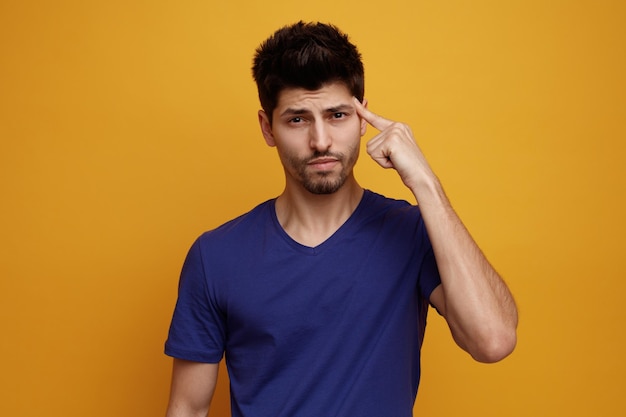 Foto gratuita hombre guapo joven serio mirando a la cámara haciendo gesto de pensamiento sobre fondo amarillo