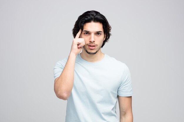 Hombre guapo joven serio mirando a la cámara mostrando gesto de pensar aislado sobre fondo blanco.