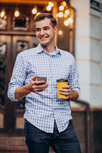 Hombre guapo joven tomando café fuera