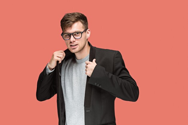 Hombre guapo joven en traje negro y gafas aisladas en rojo