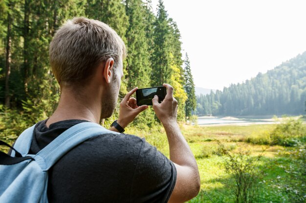 Hombre guapo joven viajando, tomando fotos de hermosas vistas a las montañas