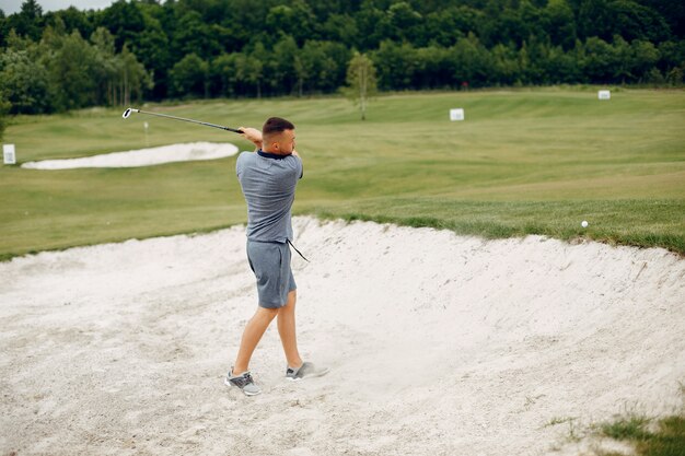 Hombre guapo jugando al golf en un campo de golf