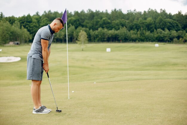 Hombre guapo jugando al golf en un campo de golf