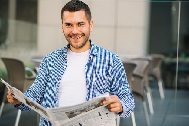 Hombre guapo leyendo periódico en café