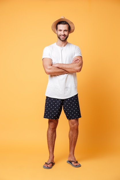 Hombre guapo con las manos juntas posando contra la pared naranja