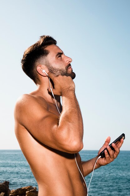 Hombre guapo mirando al cielo y escuchando música