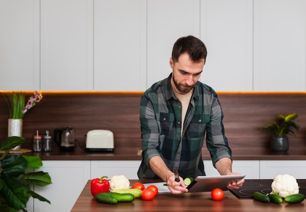 Foto gratuita hombre guapo mirando en tableta en cocina