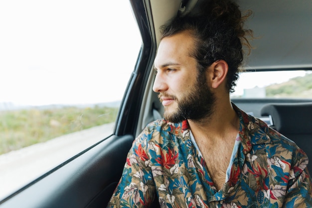 Hombre guapo mirando por la ventana del coche