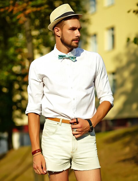 Hombre guapo modelo hipster en ropa de verano elegante posando en el sombrero