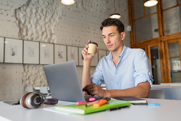 Hombre guapo moderno ocupado en su trabajo tomando café