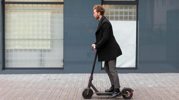 Hombre guapo montando un scooter eléctrico