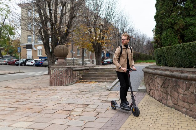 Hombre guapo montando un scooter eléctrico