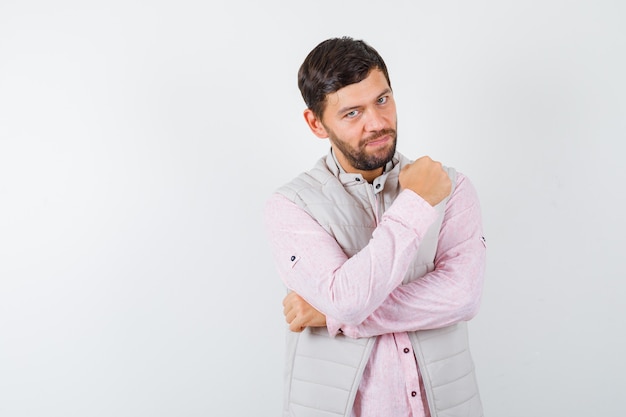 Hombre guapo mostrando los puños cerrados en chaleco, camisa y mirando confiado,