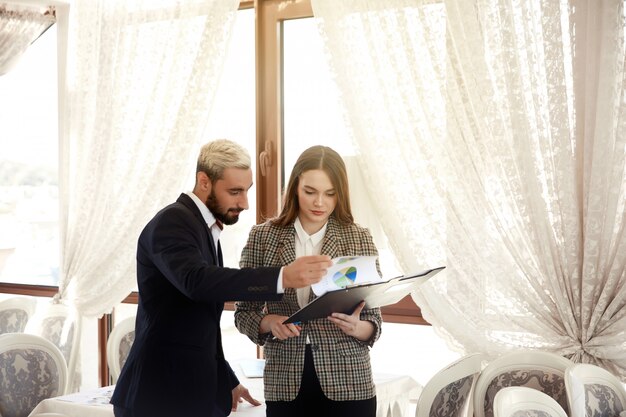 Hombre guapo y una mujer morena están mirando el diagrama, estando en la sala de luz