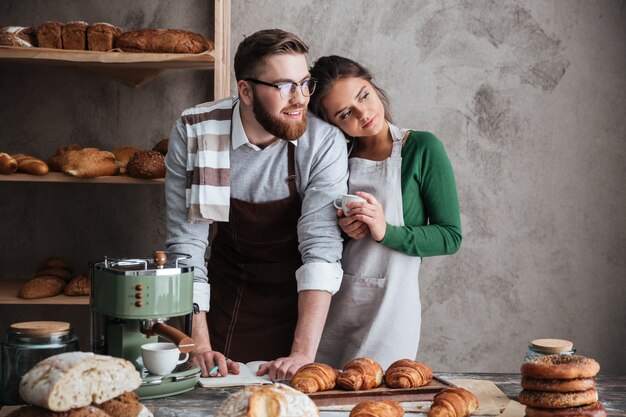 Hombre guapo y mujer de pie junto a la mesa y mirando por la ventana