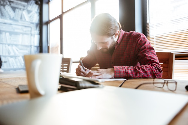 Hombre guapo en la oficina trabajando mientras escribía notas