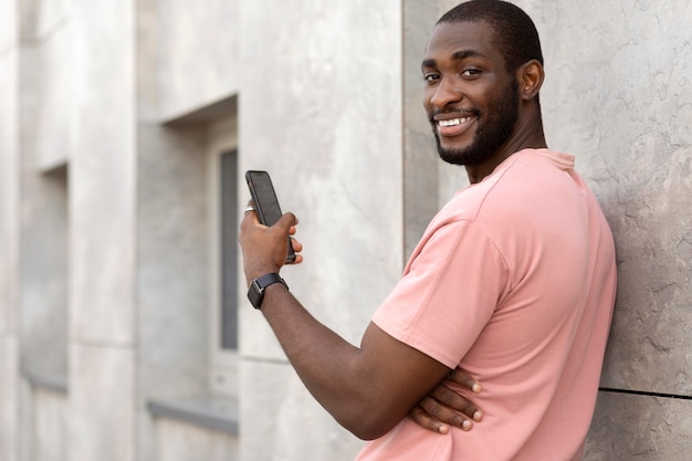 Hombre guapo pasar tiempo al aire libre y con smartphone moderno