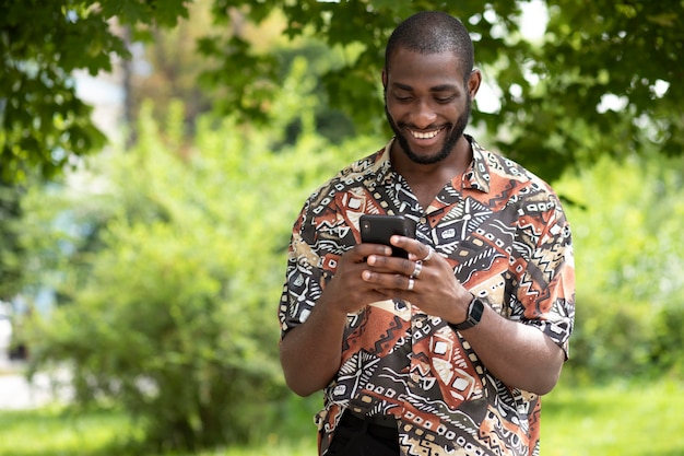 Hombre guapo pasar tiempo al aire libre y con smartphone moderno