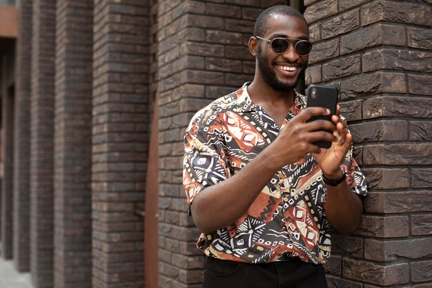 Hombre guapo pasar tiempo al aire libre y con smartphone moderno